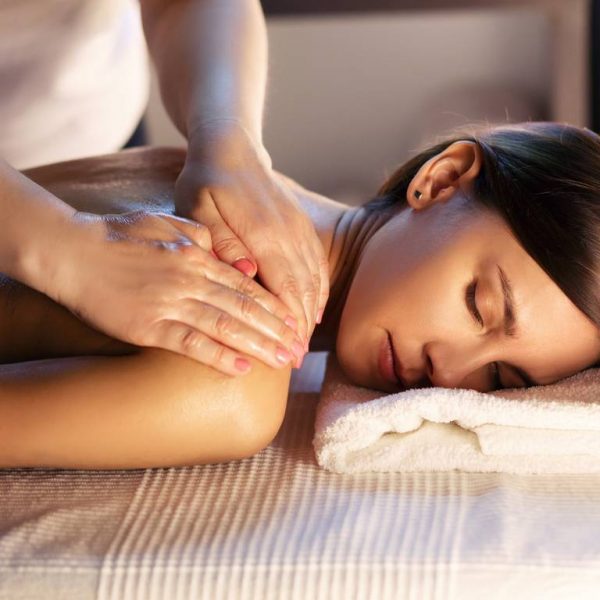 Body massage and spa treatment in modern salon with candles. Body care concept, masseur hands close up