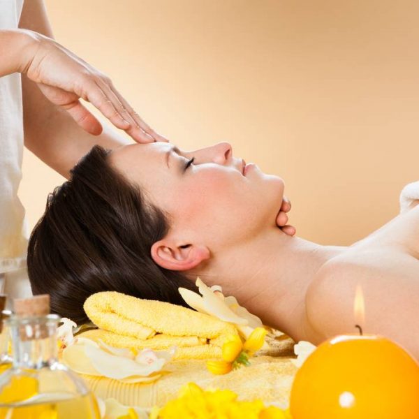 Side view of young woman receiving head massage in spa